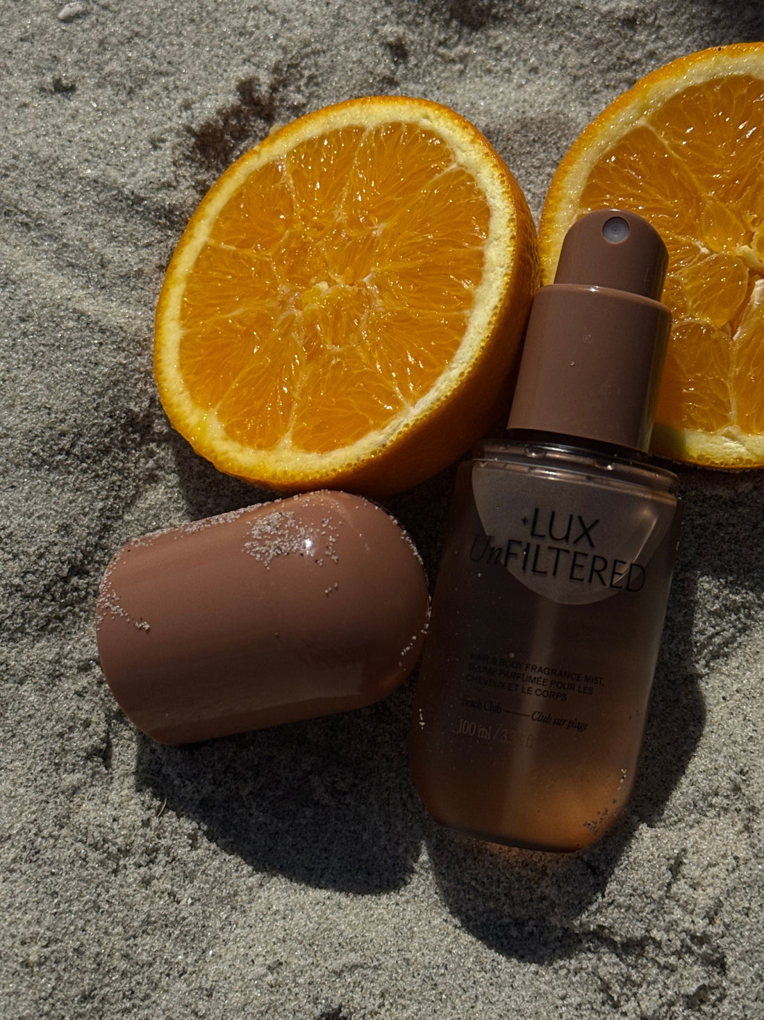 LUX Unfiltered fragrance mist beside sliced oranges on gray textured fabric