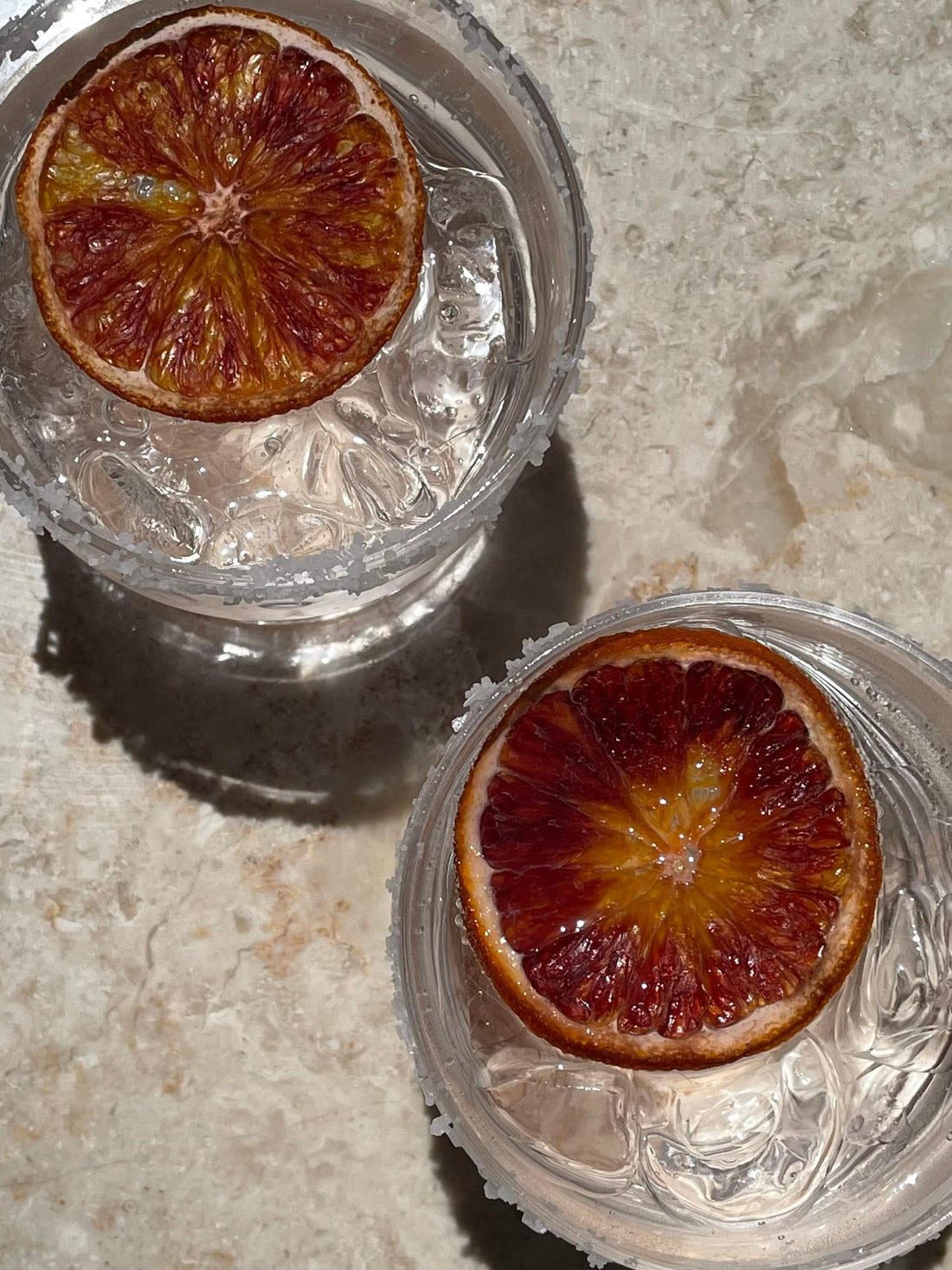 Blood orange slices in clear glass dishes on a stone countertop