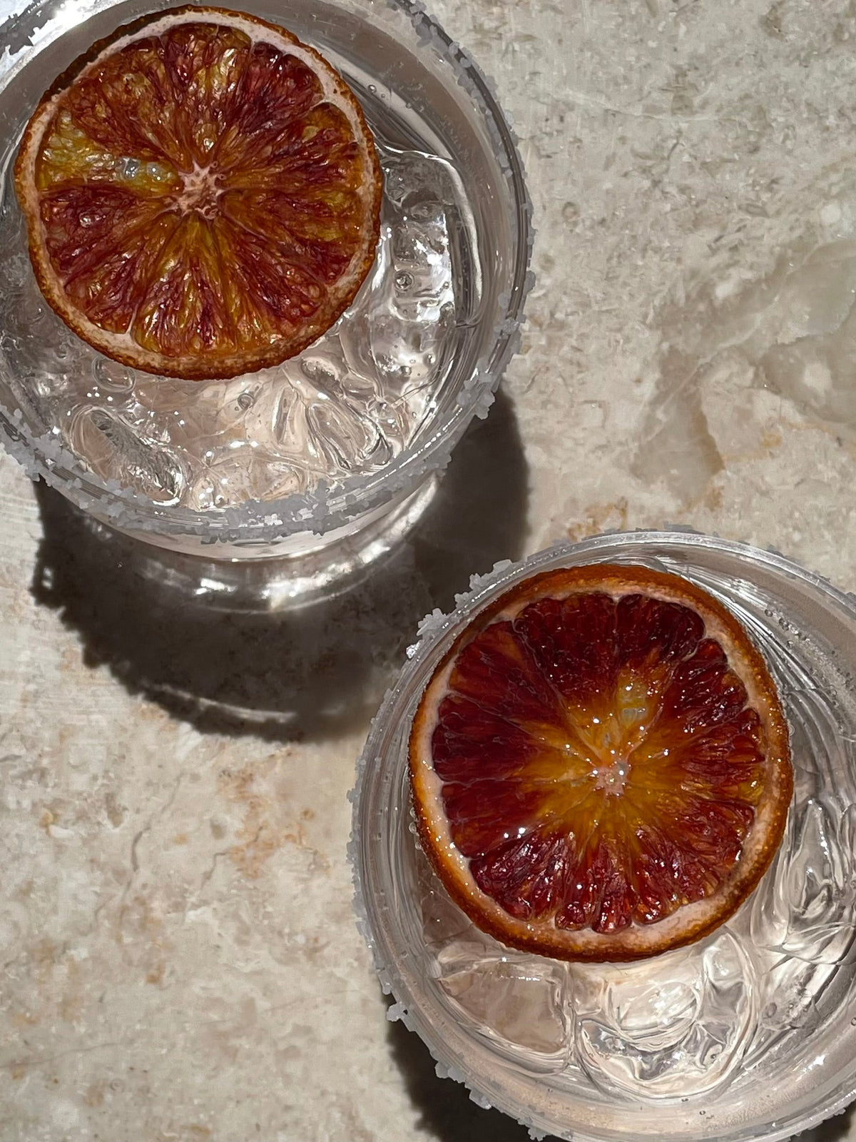 Blood orange slices in clear glass dishes on a stone countertop