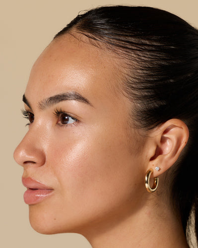LUX Unfiltered model wearing small gold hoop and diamond stud earring, close-up right profile with hair pulled back