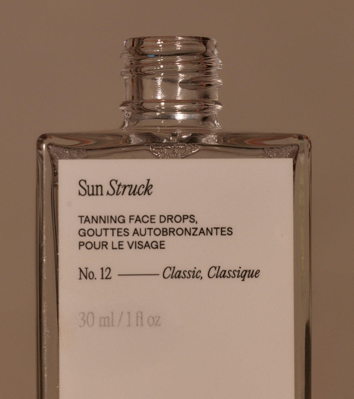 Close-up of Sun Struck Tanning Face Drops Classic bottle showing No. 12 Classic and 30 ml size against brown background