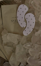 Two crescent eye patches with black plus pattern on a packet labeled + LUX UNFILTERED NO GLAM the eye mask