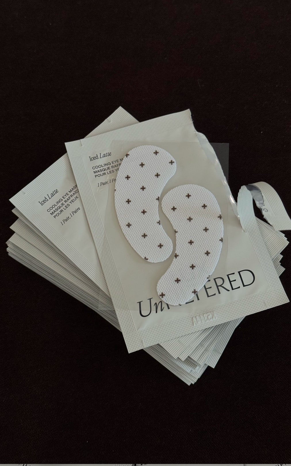 Stack of Unfiltered cooling eye mask packets (Iced Latte); visible text: Iced Latte, COOLING EYE, 1 Pair, 1 Paire