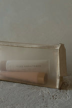 Sheer beige mesh cosmetic pouch with two tubes inside, one labeled LUX UNFILTERED